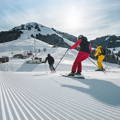 Drei Skifahrer bei der Abfahrt vor Bergkulisse der Hohen Salve