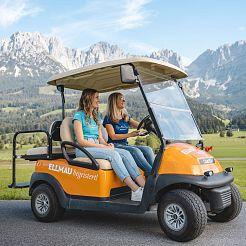 Zwei Frauen fahren in orangen Golfcar