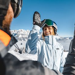 Zwei Skifahrer heben die Hände zum Einklatschen