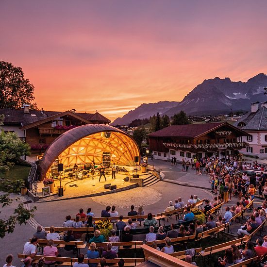 Blick auf erhellte Freilichtbühne und Publikum am Abend